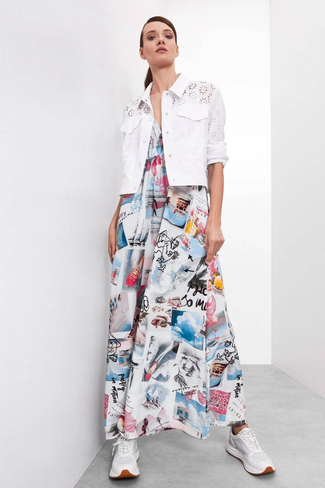 Femme portant une robe à bretelles imprimée et une veste blanche, look décontracté avec baskets gris.