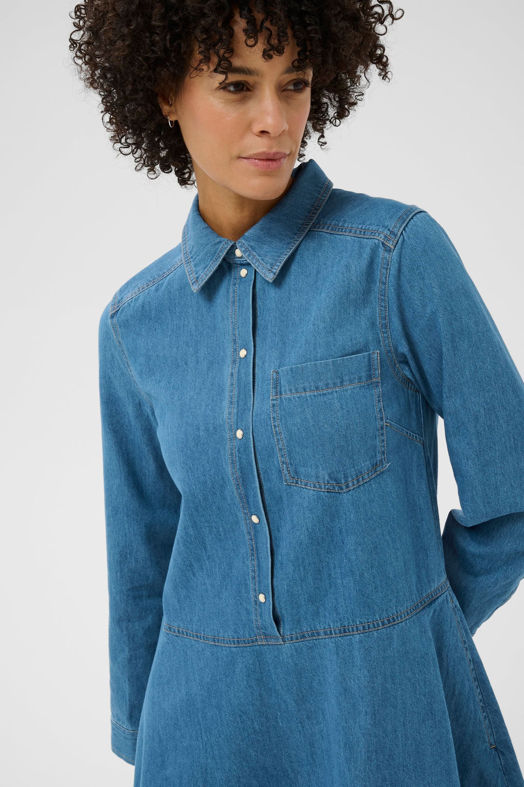 Femme portant la Robe chemise Augustine en denim avec coupe évasée et col structuré, style décontracté et intemporel.