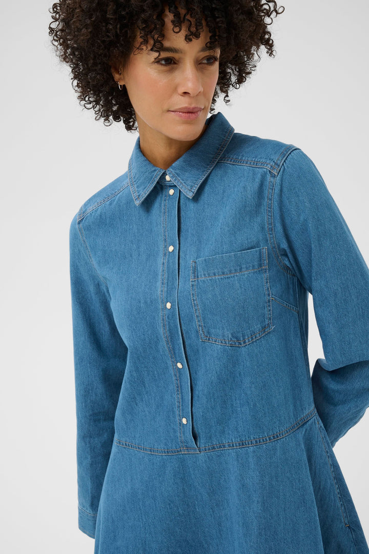 Femme portant la Robe chemise Augustine en denim avec coupe évasée et col structuré, style décontracté et intemporel.