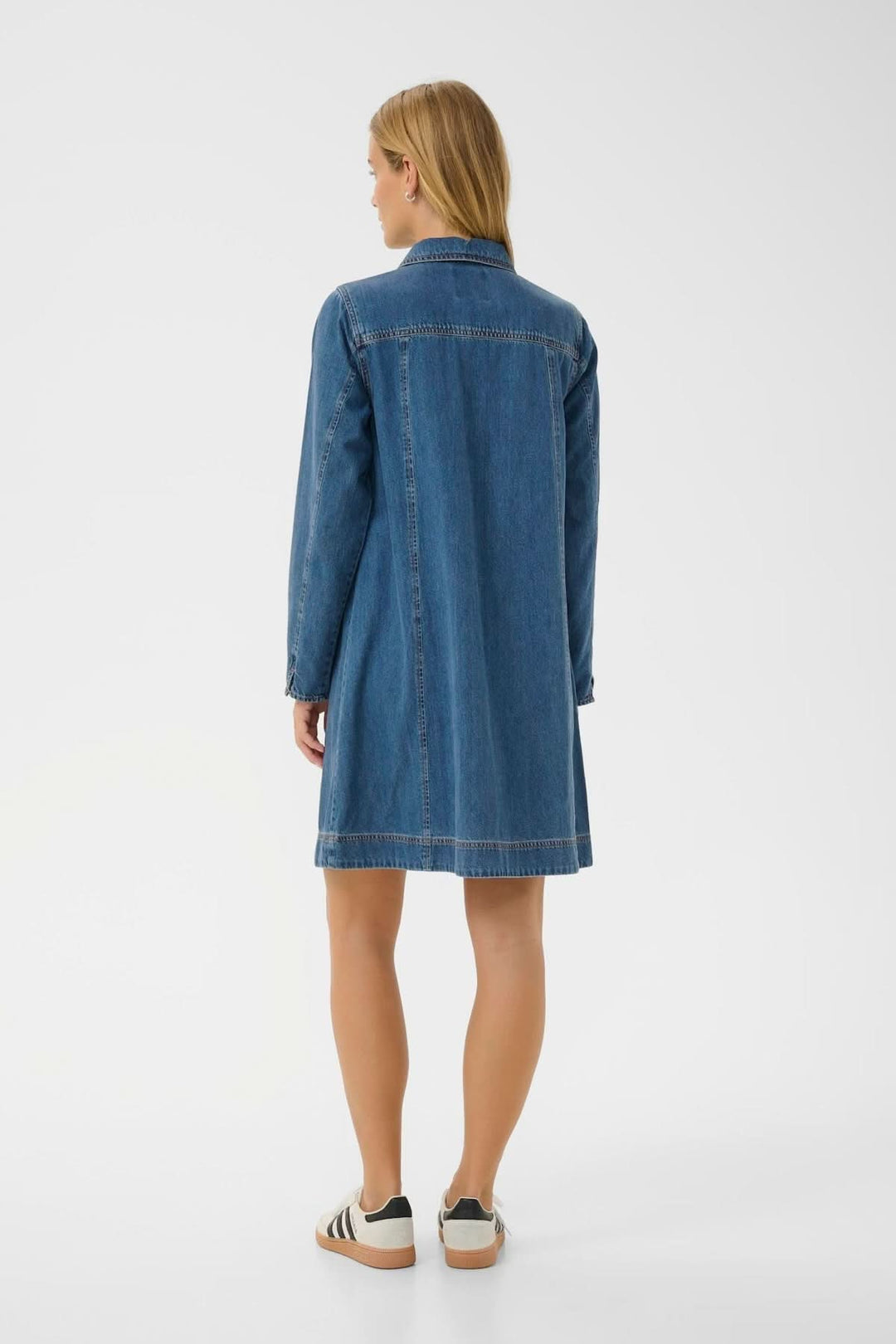 Femme portant une robe en denim au style décontracté, longueur au-dessus du genou et col chemise, vue de dos.