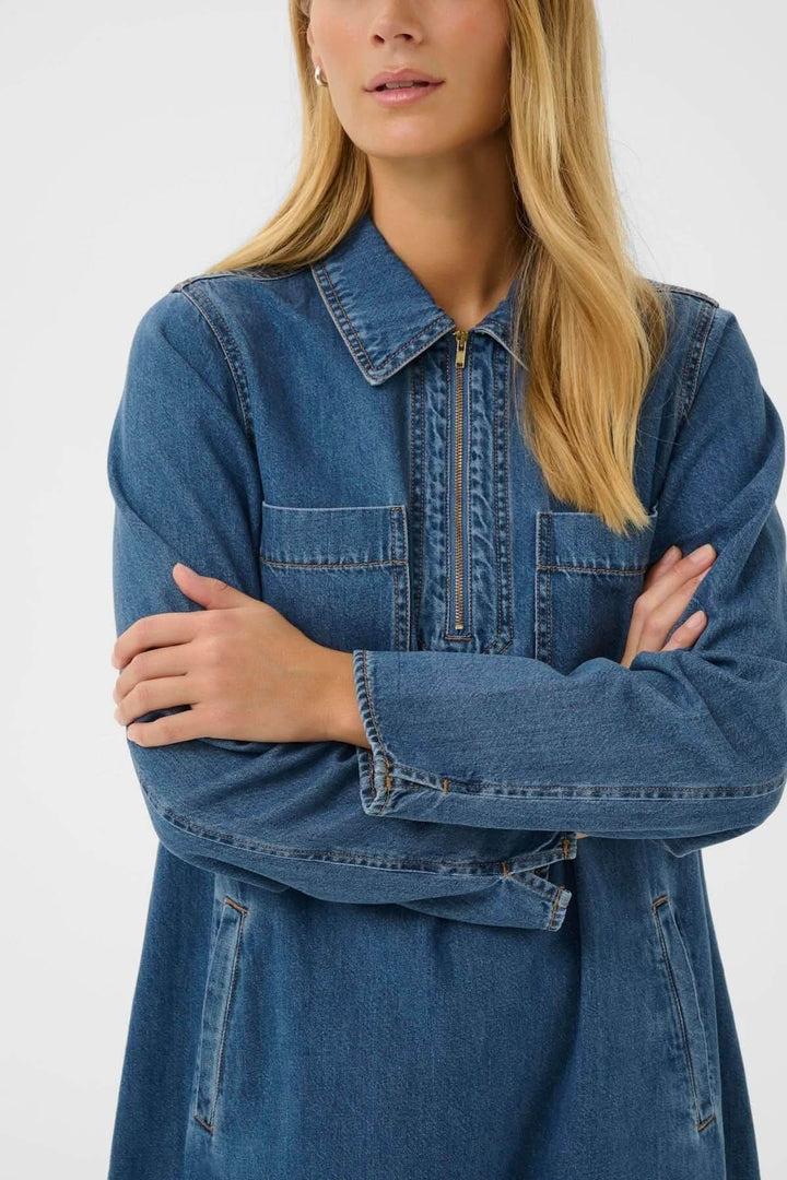 Robe en denim avec col chemise zippé, coupe droite ample, et longueur au-dessus du genou pour un style décontracté et moderne.
