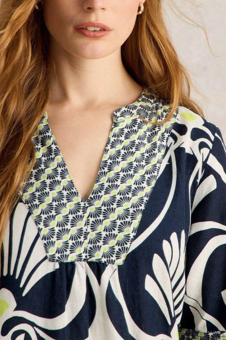 Détail d'une robe en lin cendré avec col en V et imprimé graphique, style chic et décontracté.