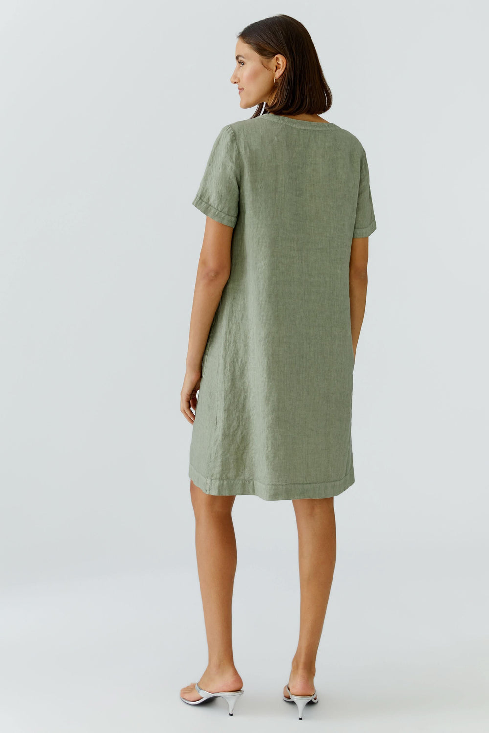 Femme portant une robe en lin à manches courtes, coupe droite, vue de dos.