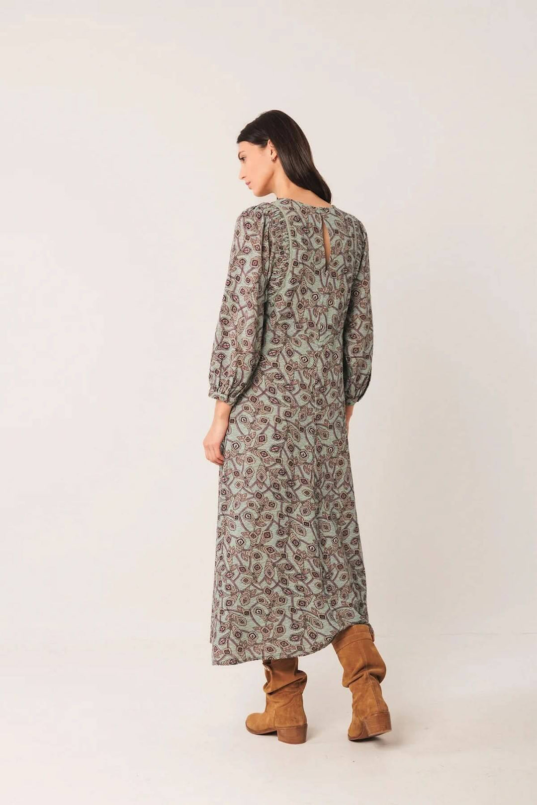Robe longue à motif géométrique avec manches longues légèrement bouffantes, encolure ronde, portée avec des bottes en daim pour un look bohème chic.