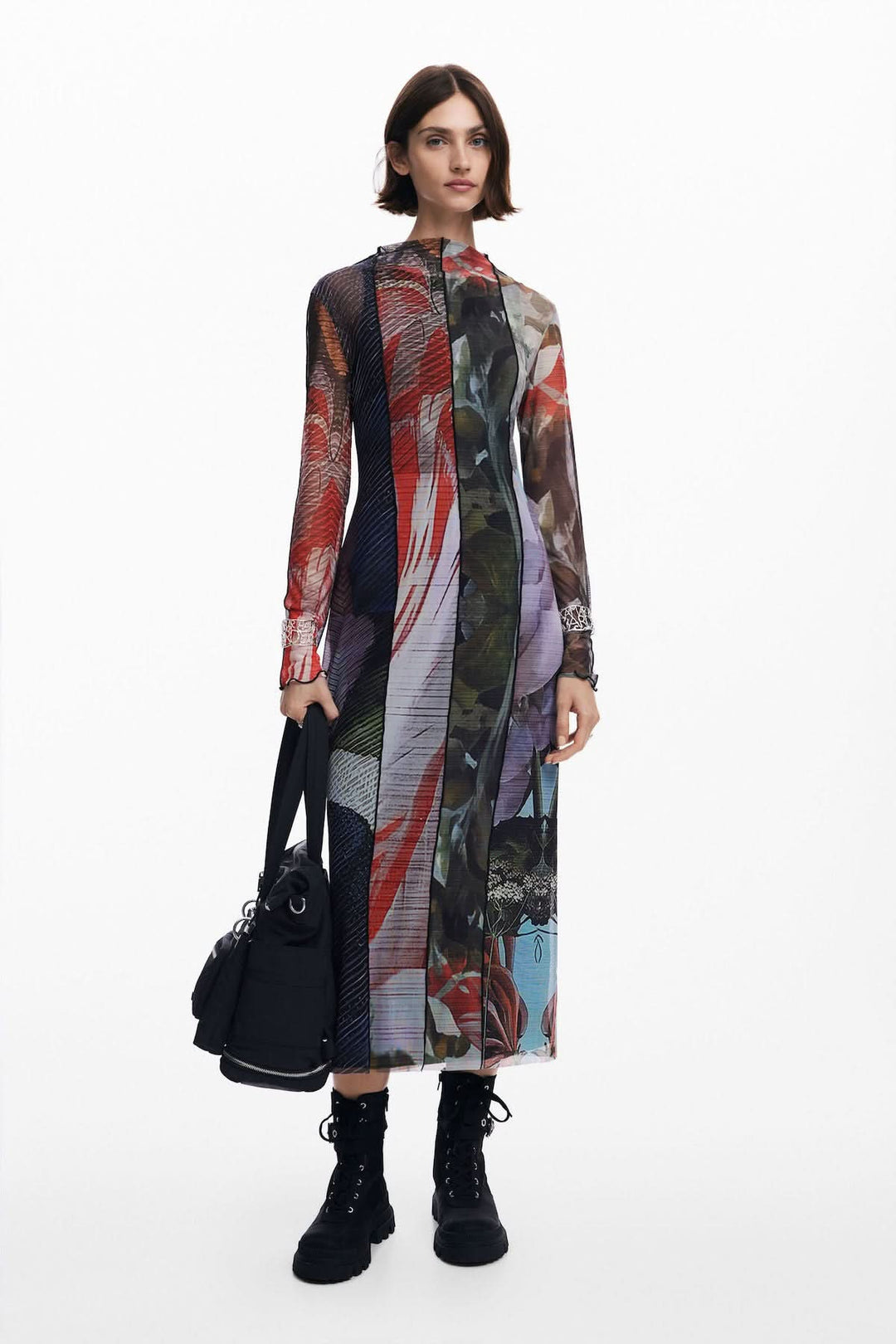 Robe longue en tulle imprimé floral, avec manches longues et col ras du cou, portée par un modèle avec un sac.