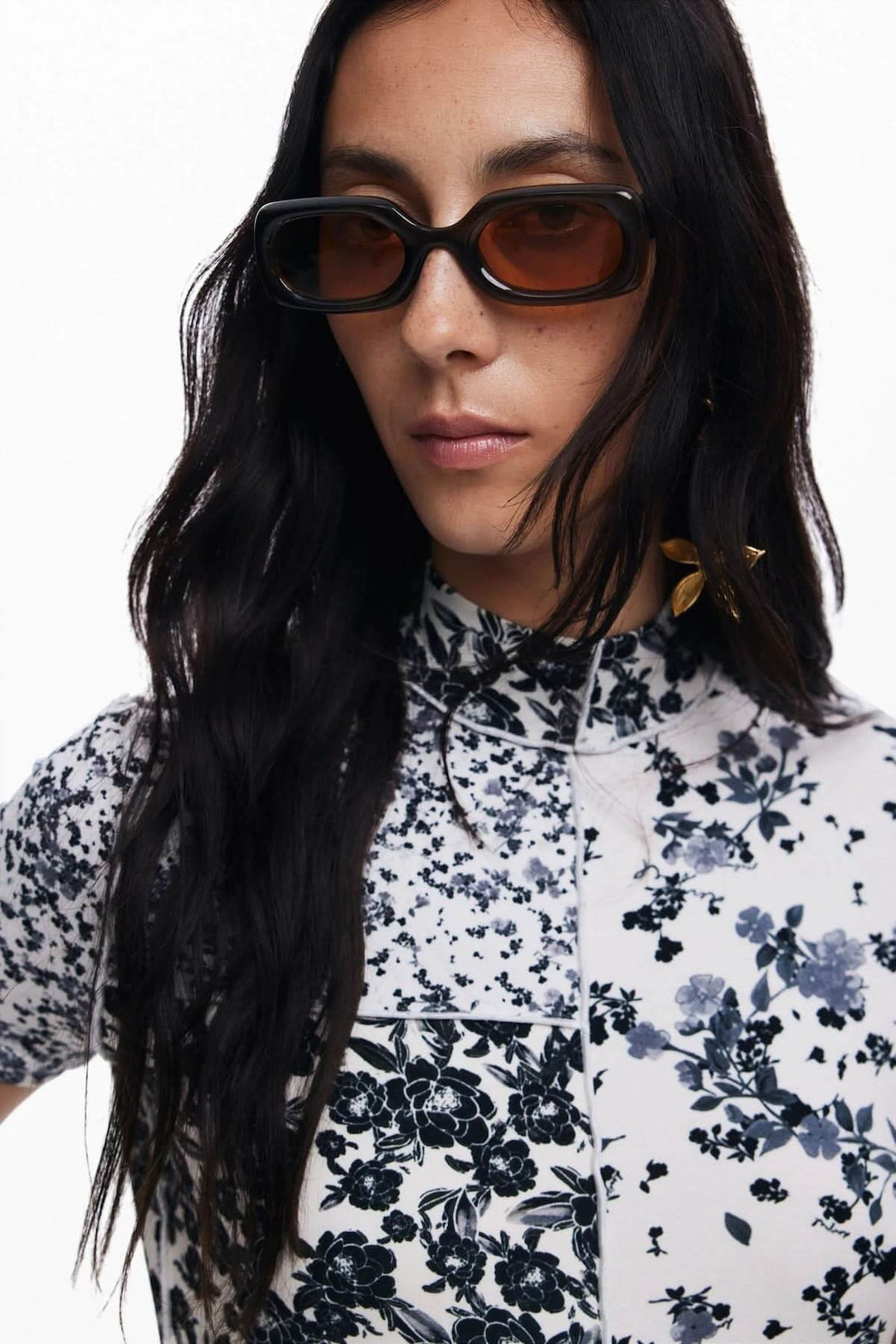 Femme avec lunettes de soleil, portant une robe longue imprimée floral à col montant et manches courtes.
