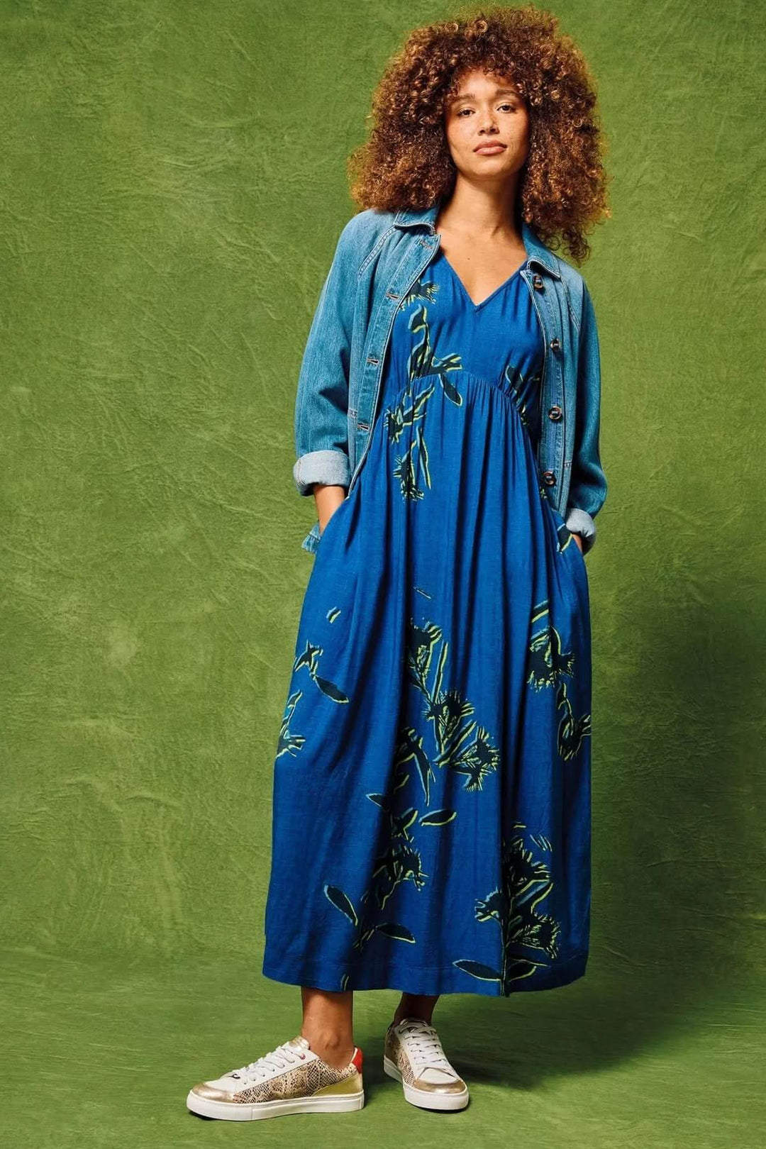 Robe mi-longue Lucy en viscose Ecovero, avec motif, portée avec veste en jean et sneakers.