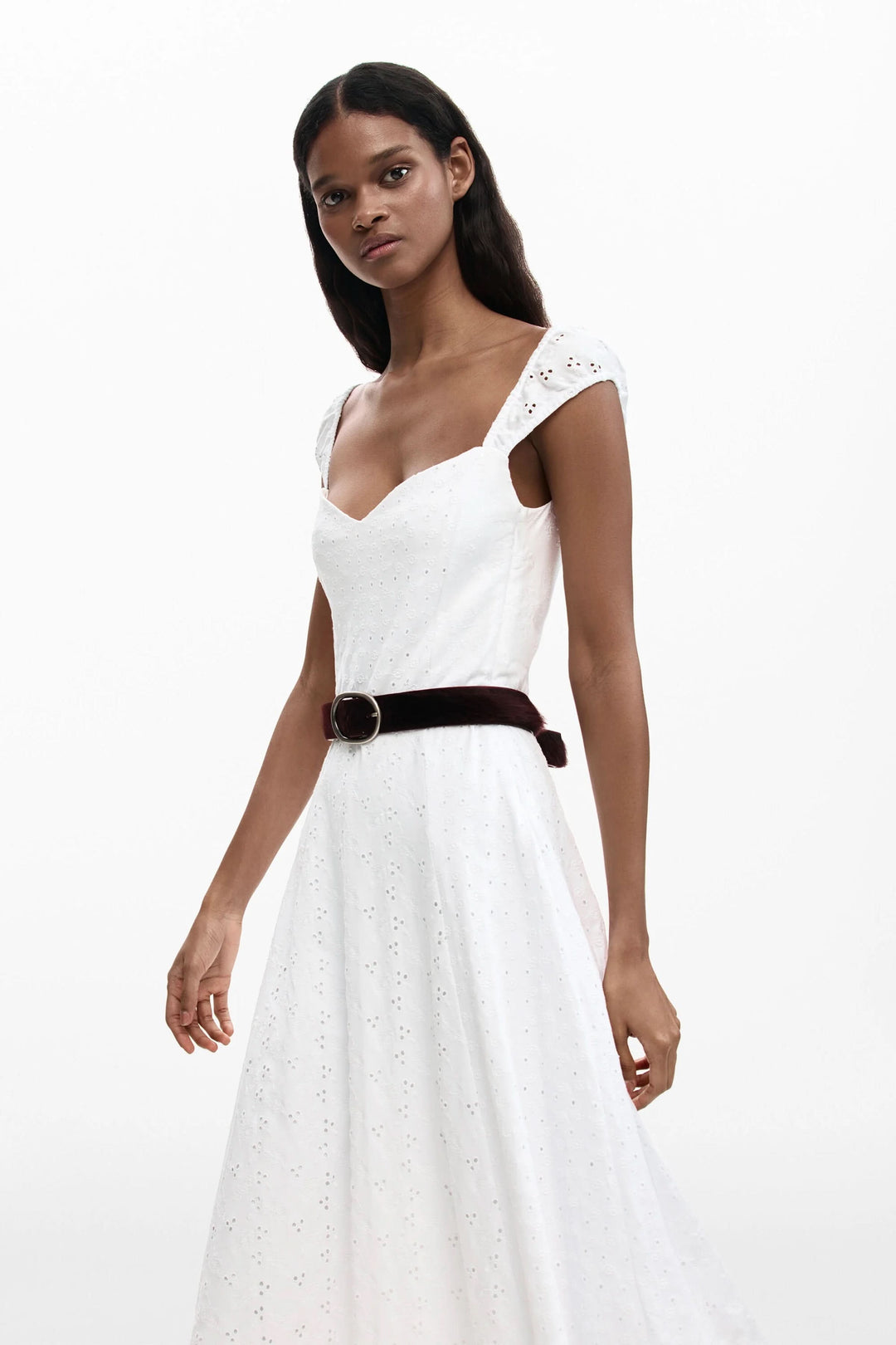 Robe midi brodée blanche avec encolure cœur et jupe évasée, portée par un modèle. Élégance estivale chic.