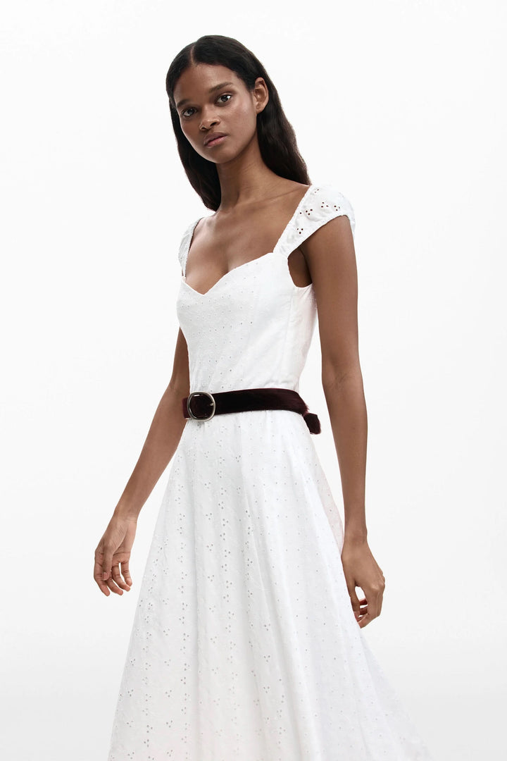 Robe midi brodée blanche avec encolure cœur et jupe évasée, portée par un modèle. Élégance estivale chic.