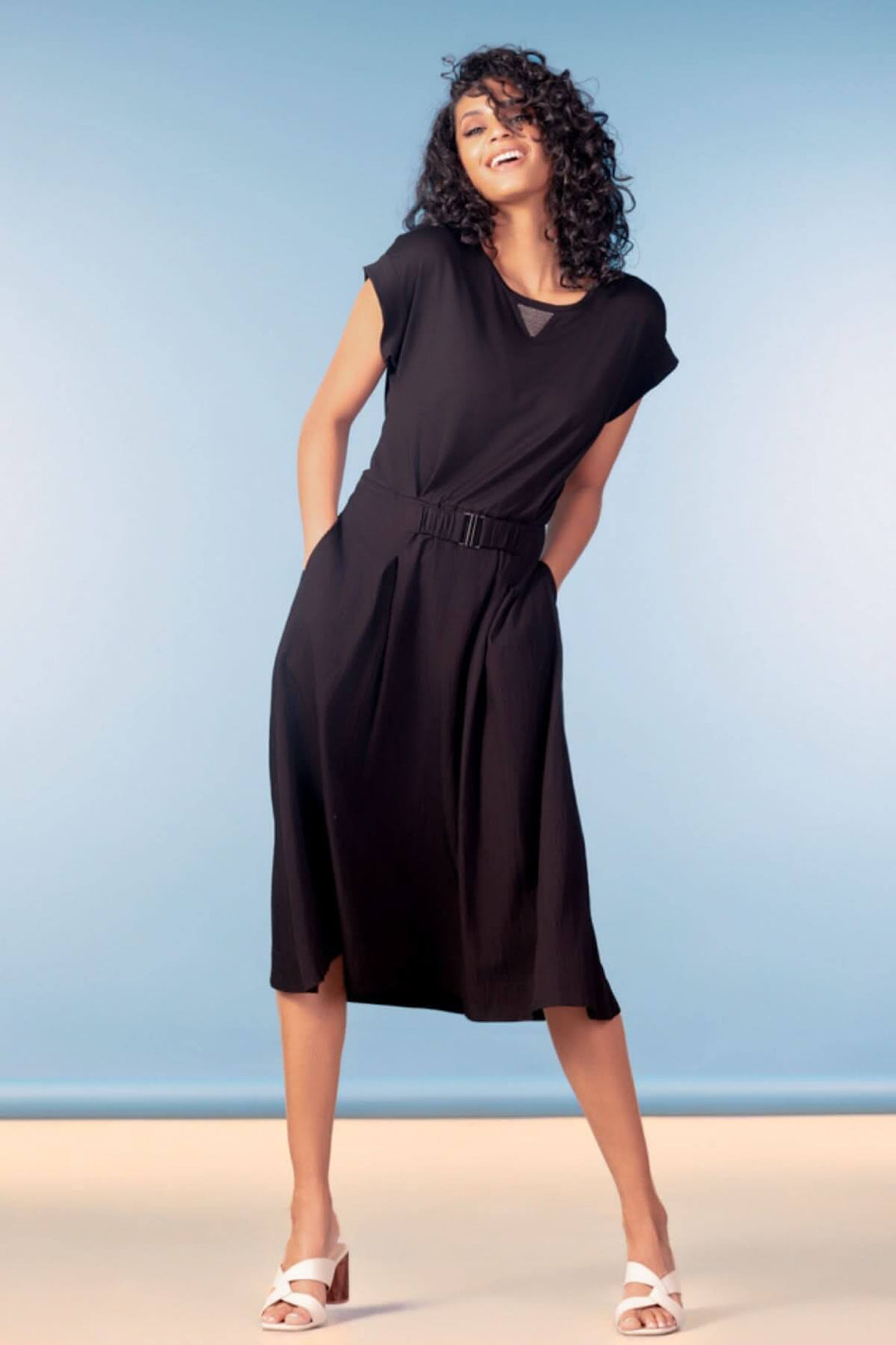 Femme portant une robe midi fluide à taille ceinturée, manches courtes, allure décontractée et élégante.