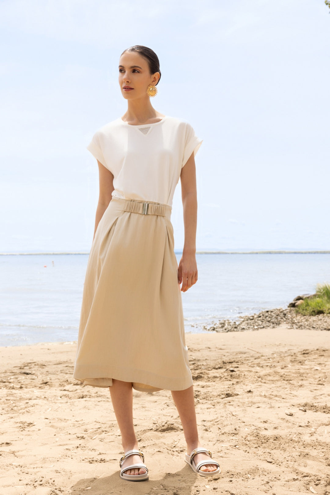 Femme portant une robe midi fluide à taille ceinturée sur la plage, décontractée et élégante.