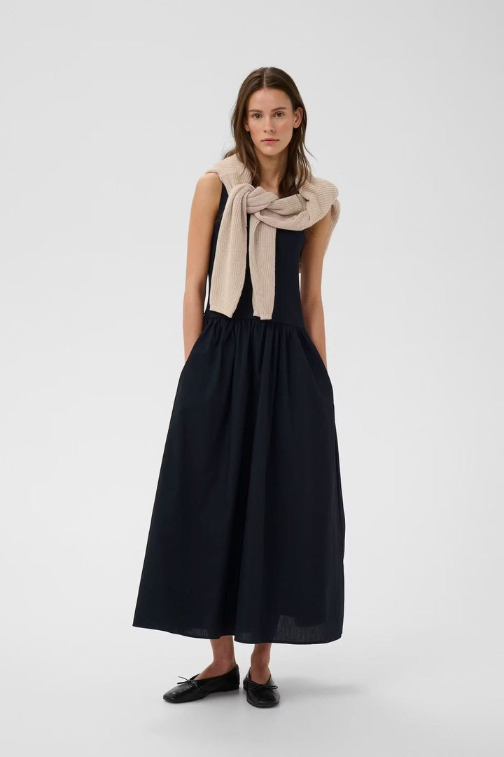 Femme portant une robe midi sans manches Dagnama, silhouette élégante et féminine.