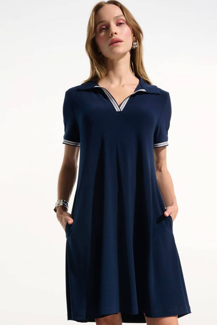 Femme portant une robe polo à col contrasté bleue, coupe ample et fluide, avec un col en V et bordures rayées, idéale pour l&