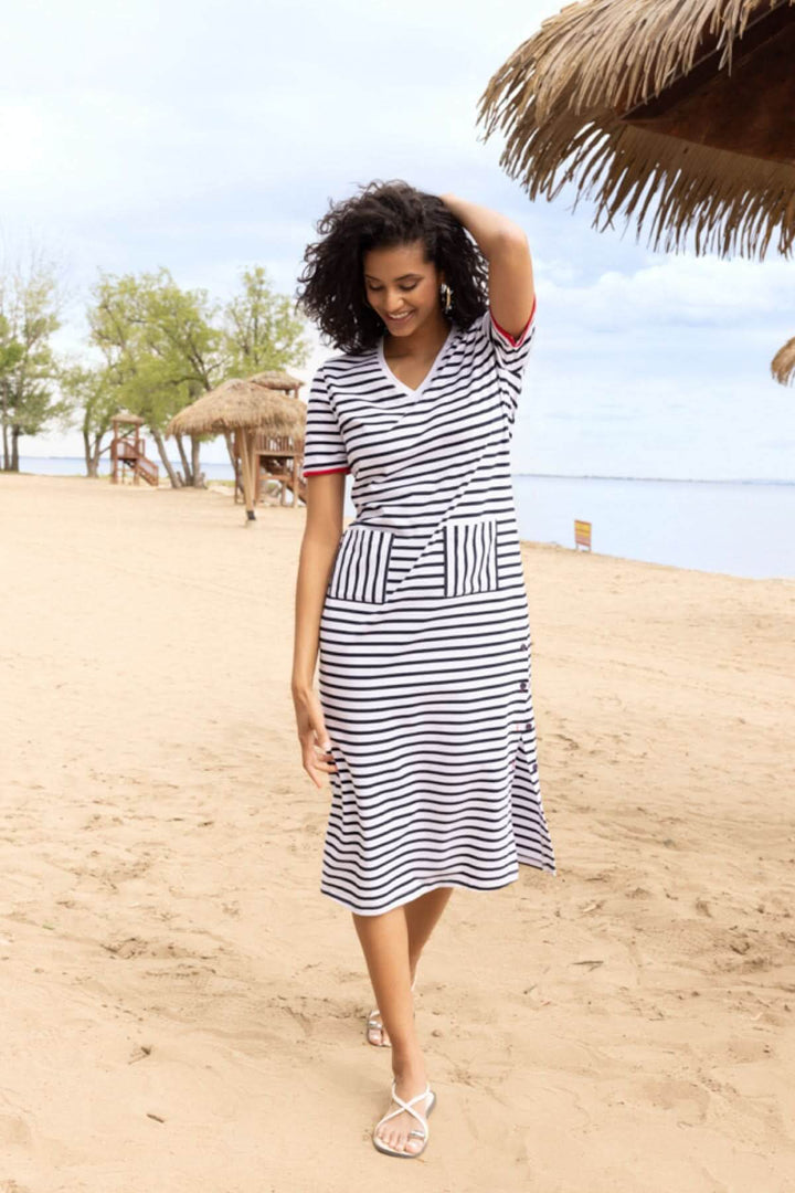 Femme portant une robe rayée à encolure en V sur une plage, montrant une silhouette décontractée et élégante.