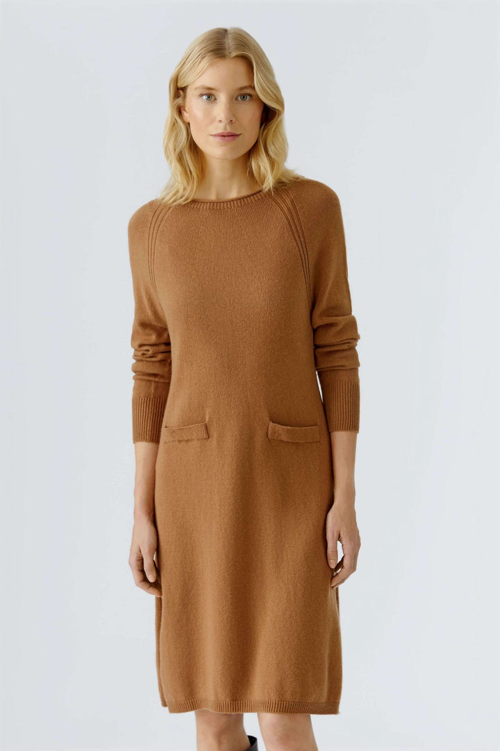 Femme portant une robe tricotée à manches longues et poches plaquées, style minimaliste automnal.