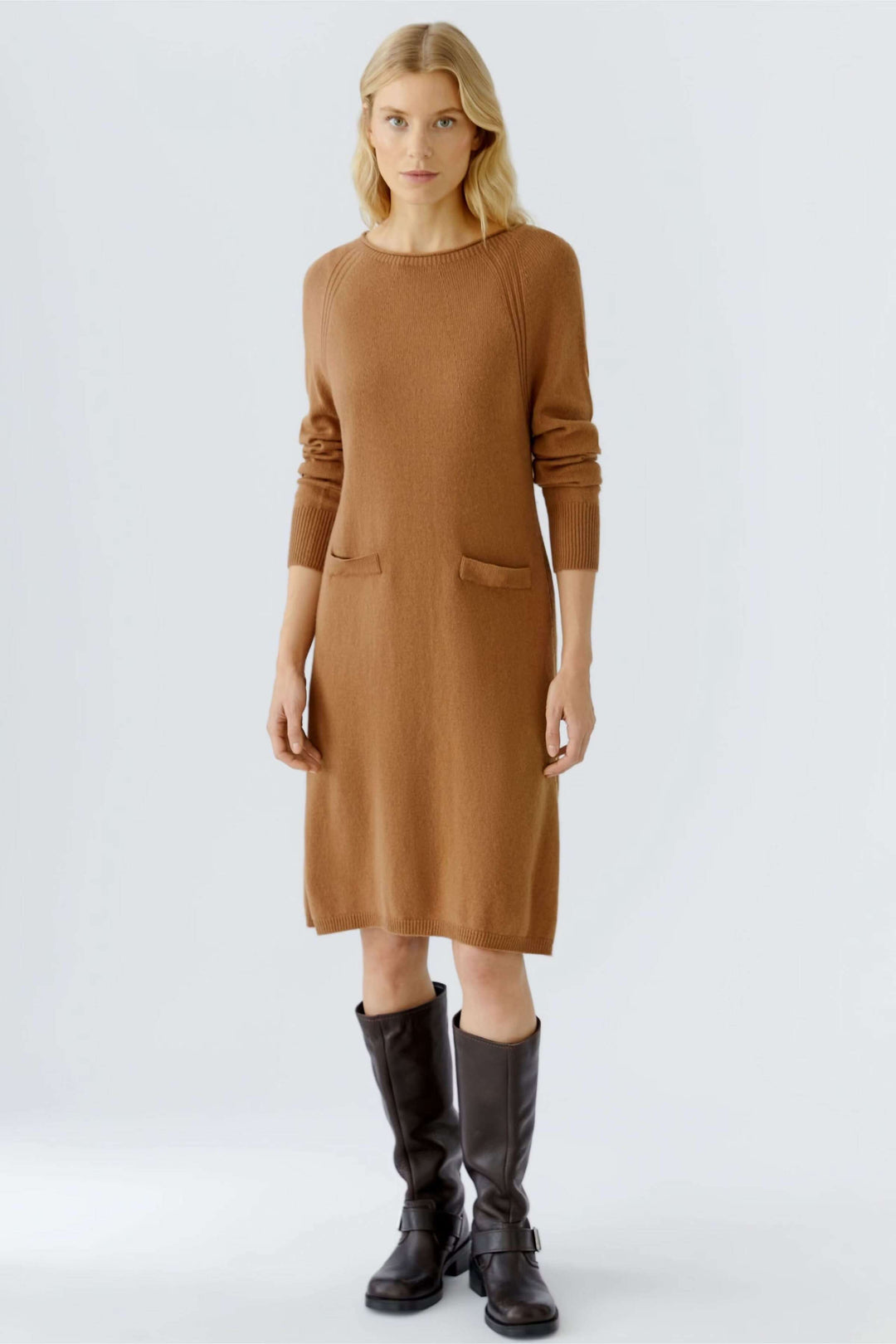 Robe tricotée à manches longues et poches plaquées sur modèle, tenue chic automnale avec bottes hautes, détails côtelés élégants.