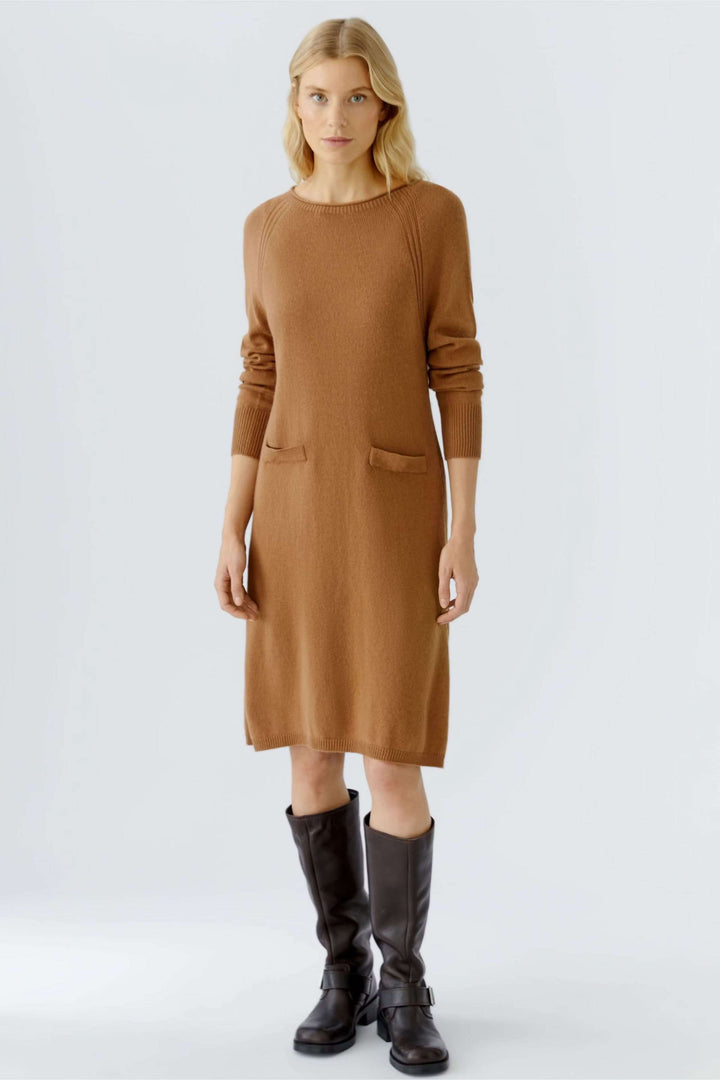 Robe tricotée à manches longues et poches plaquées sur modèle, tenue chic automnale avec bottes hautes, détails côtelés élégants.