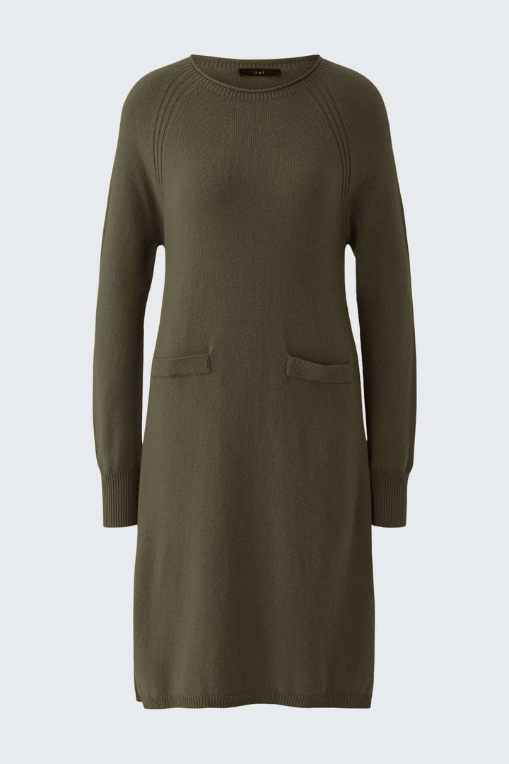 Robe tricotée à manches longues et poches plaquées verte sur fond clair, avec une coupe décontractée et finitions côtelées.