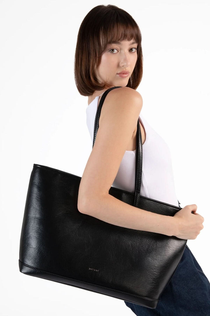 Femme portant un sac fourre-tout Eliza élégant en cuir noir, mettant en avant sa simplicité et sa praticité.