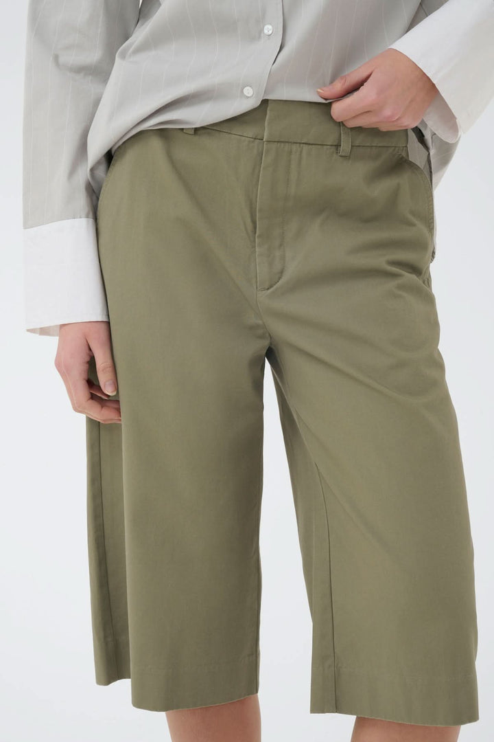 Short bermuda structuré Diazi en kaki, coupe droite élégante, poches latérales, fermeture à bouton et zip, look moderne et épuré.