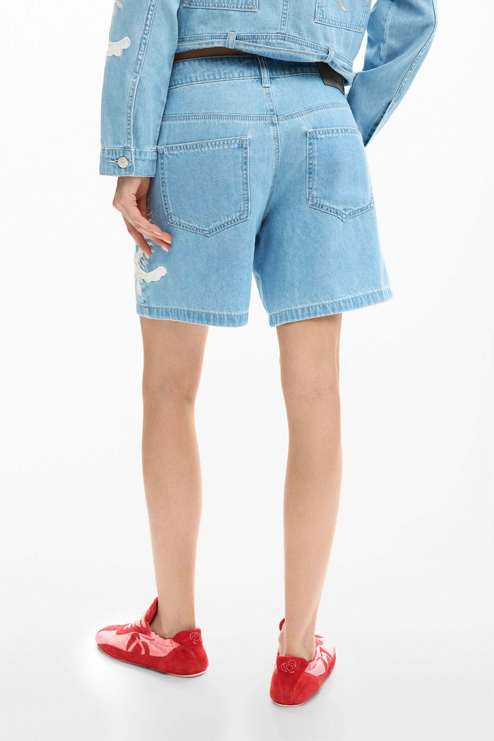 Dos d'un short en jean brodée avec veste assortie, accent graphique et coupe droite pour une tenue estivale polyvalente.