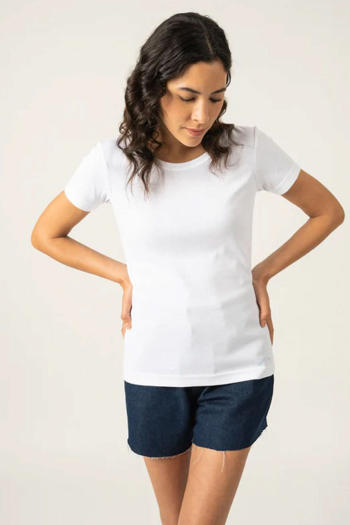 Femme portant un t-shirt blanc ajusté avec manches courtes et shorts en denim.