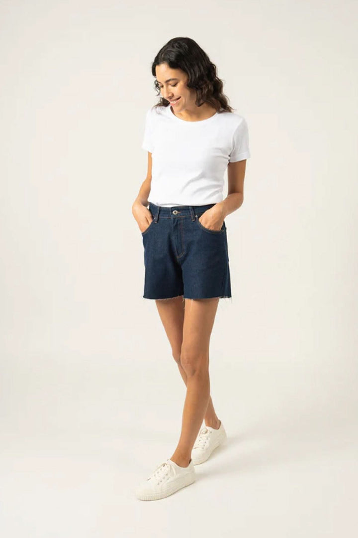 Femme portant un t-shirt blanc avec un short en jean, style décontracté et élégant.