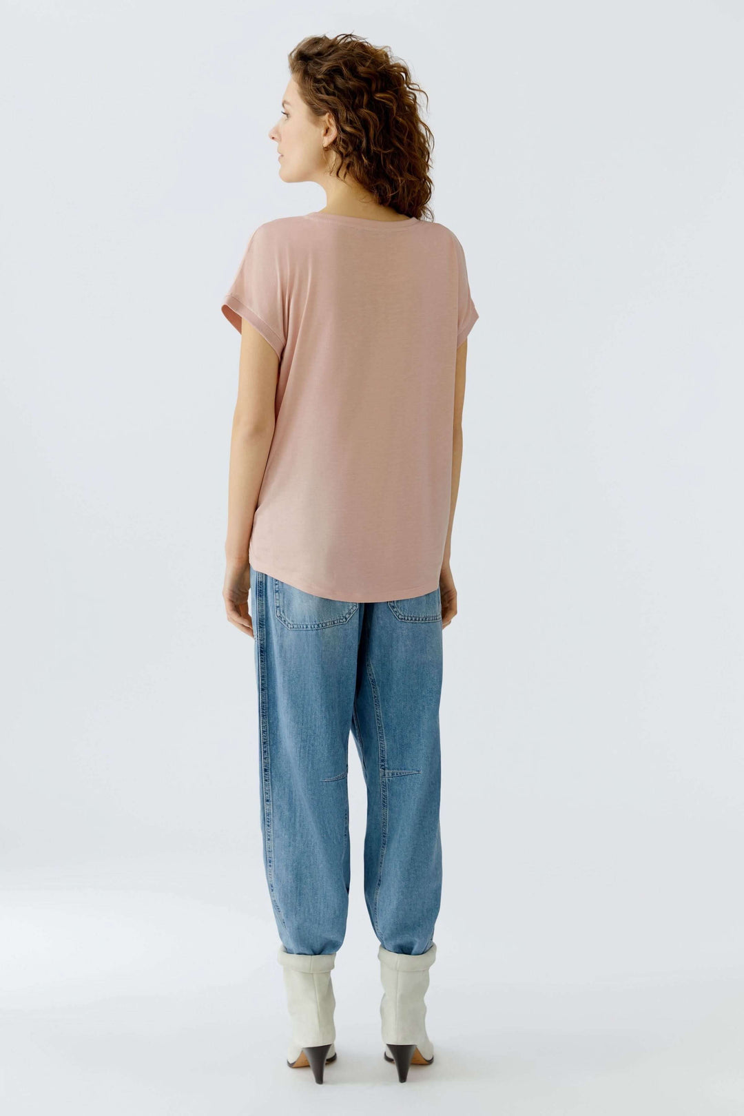 Femme debout portant un T-shirt Ayano fluide avec manches courtes retroussées, vue de dos, style décontracté et épuré.