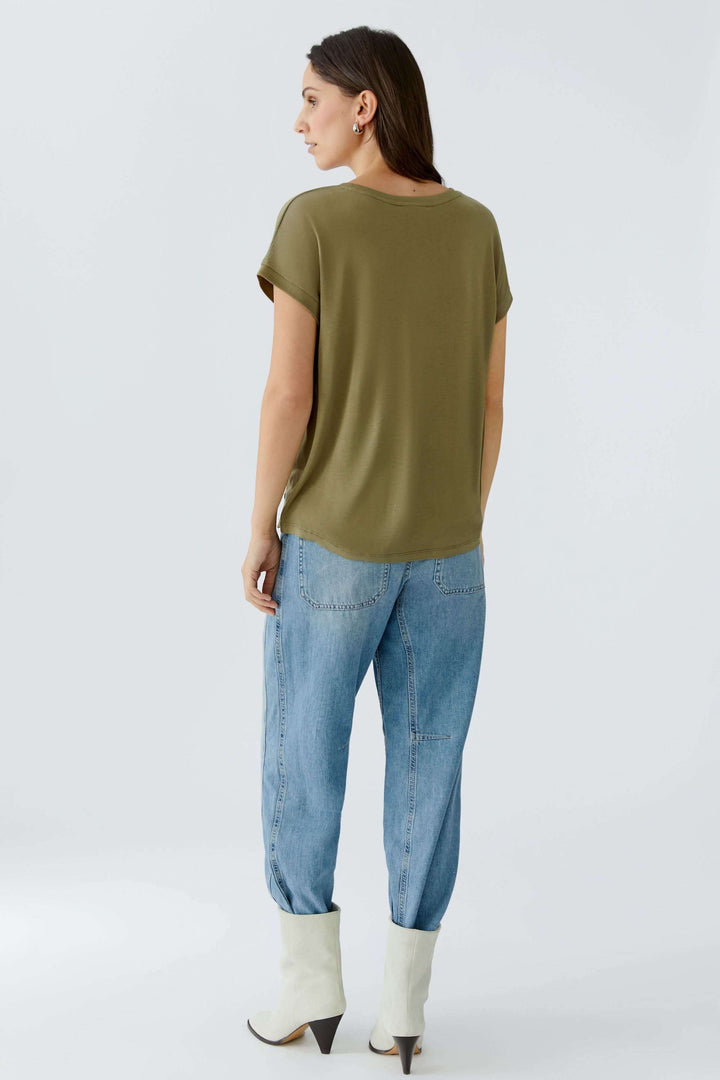 Femme portant le T-shirt Ayano fluide avec manches retroussées et coupe droite, vue de dos, couleur olive, style décontracté.