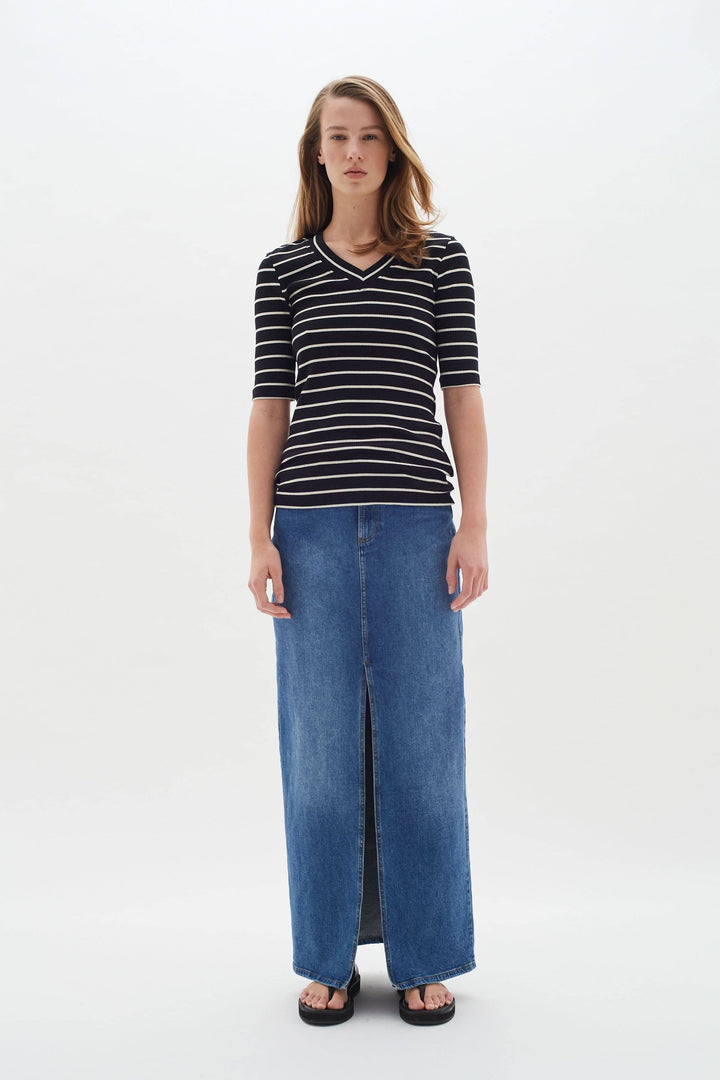 T-shirt Dagna à rayures noires et blanches, coupe ajustée, porté avec une jupe longue en denim.