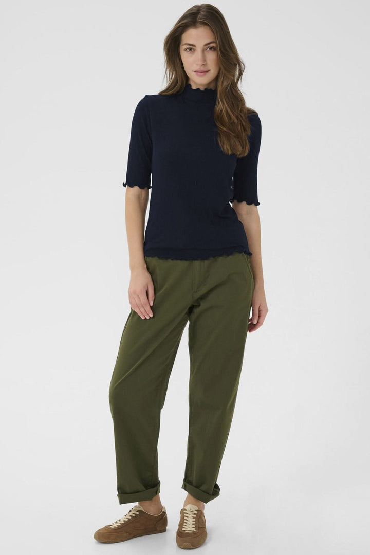 Femme portant le T-shirt Ribba à col montant festonné et manches mi-longues, coupe ajustée en maille côtelée extensible.