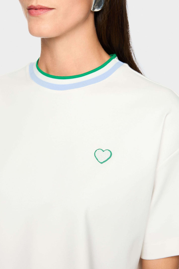 Femme portant un T-shirt avec détails en forme de cœur et à rayures, col à liseré contrastant, coupe ample.