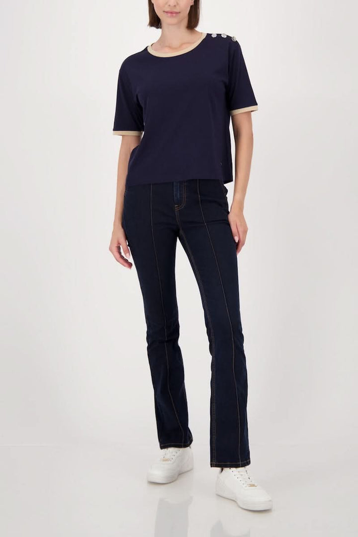 Modele portant un T-shirt à boutons décoratifs sur l’épaule, finitions contrastantes, jersey doux, look décontracté et confortable.