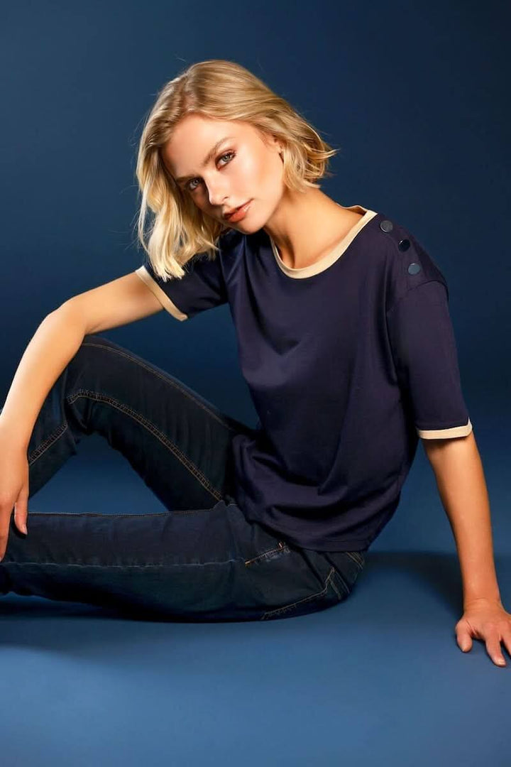 Femme portant un T-shirt à boutons décoratifs sur l’épaule avec finitions contrastantes, style décontracté et chic.