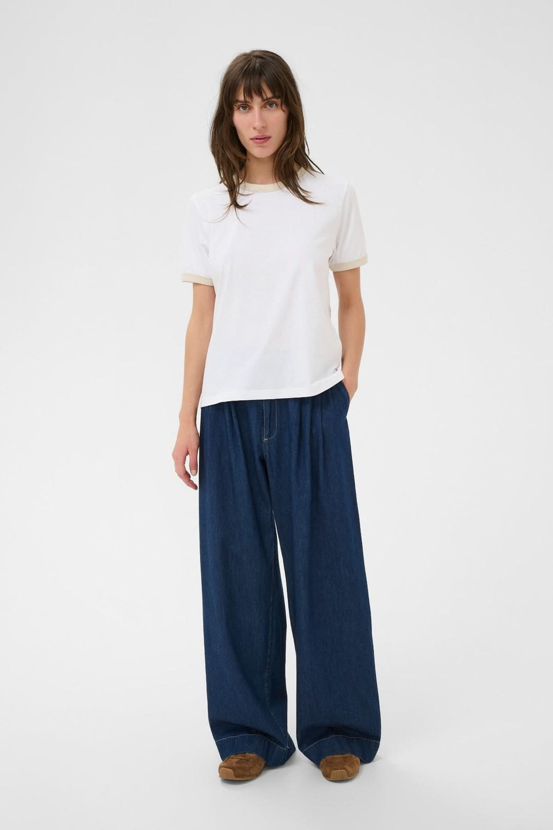 Femme portant le T-shirt à col contrastant Angelita avec un col rond et manches courtes, associé à un pantalon ample.