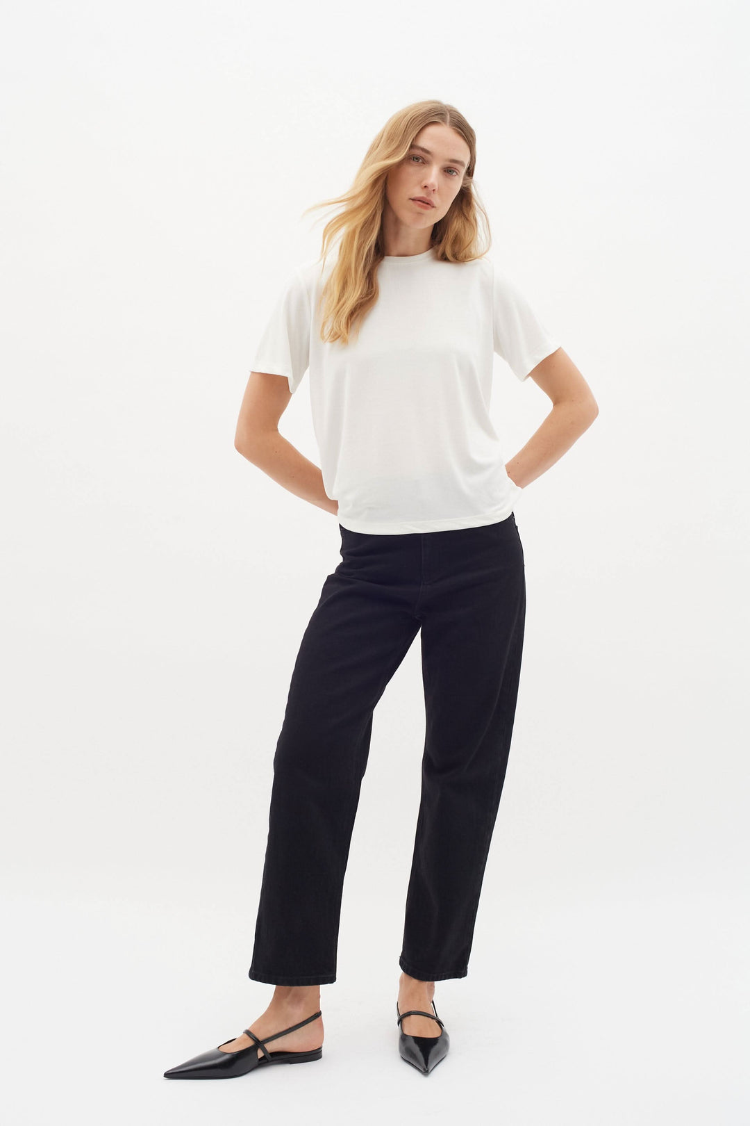 T-shirt col rond blanc Liliana porté avec un pantalon noir, style décontracté et élégant.