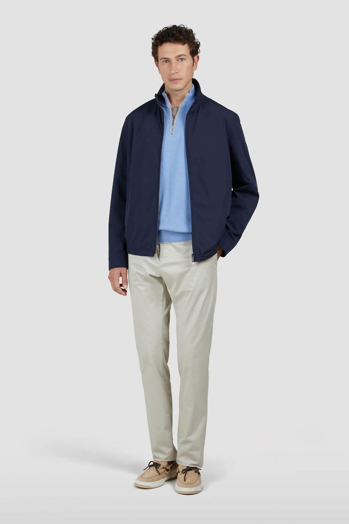 Homme portant une veste marine avec un polo bleu et un pantalon clair, look décontracté et élégant.
