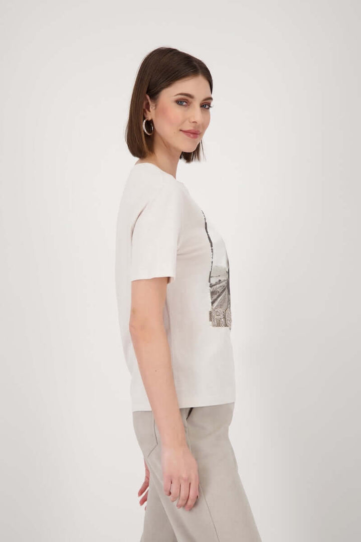 Femme portant un t-shirt imprimé avec motif « road trip », manches courtes et strass, style casual chic.