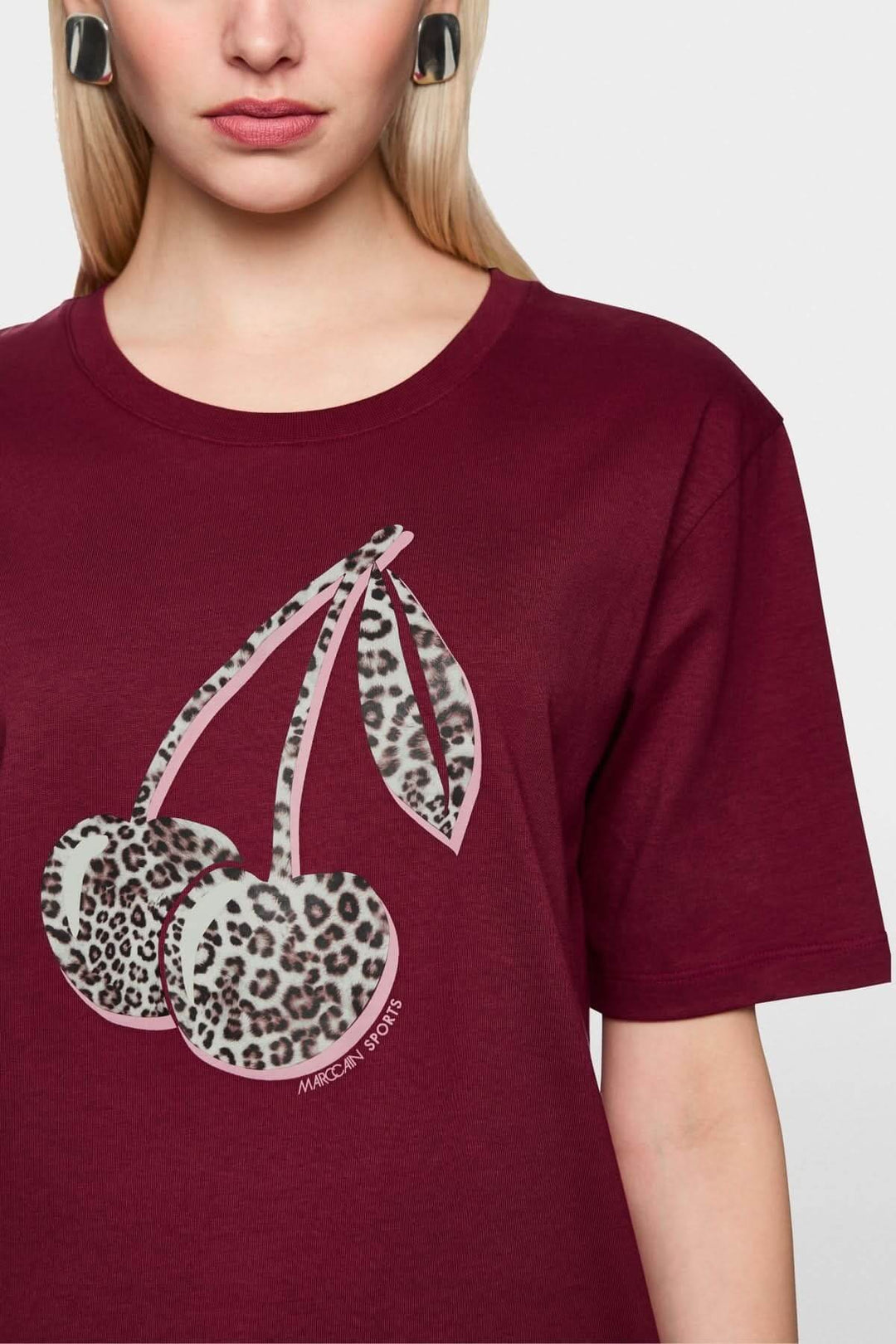 Femme portant un t-shirt imprimé cerises léopard en coton biologique, coupe droite et manches courtes, couleur bordeaux.