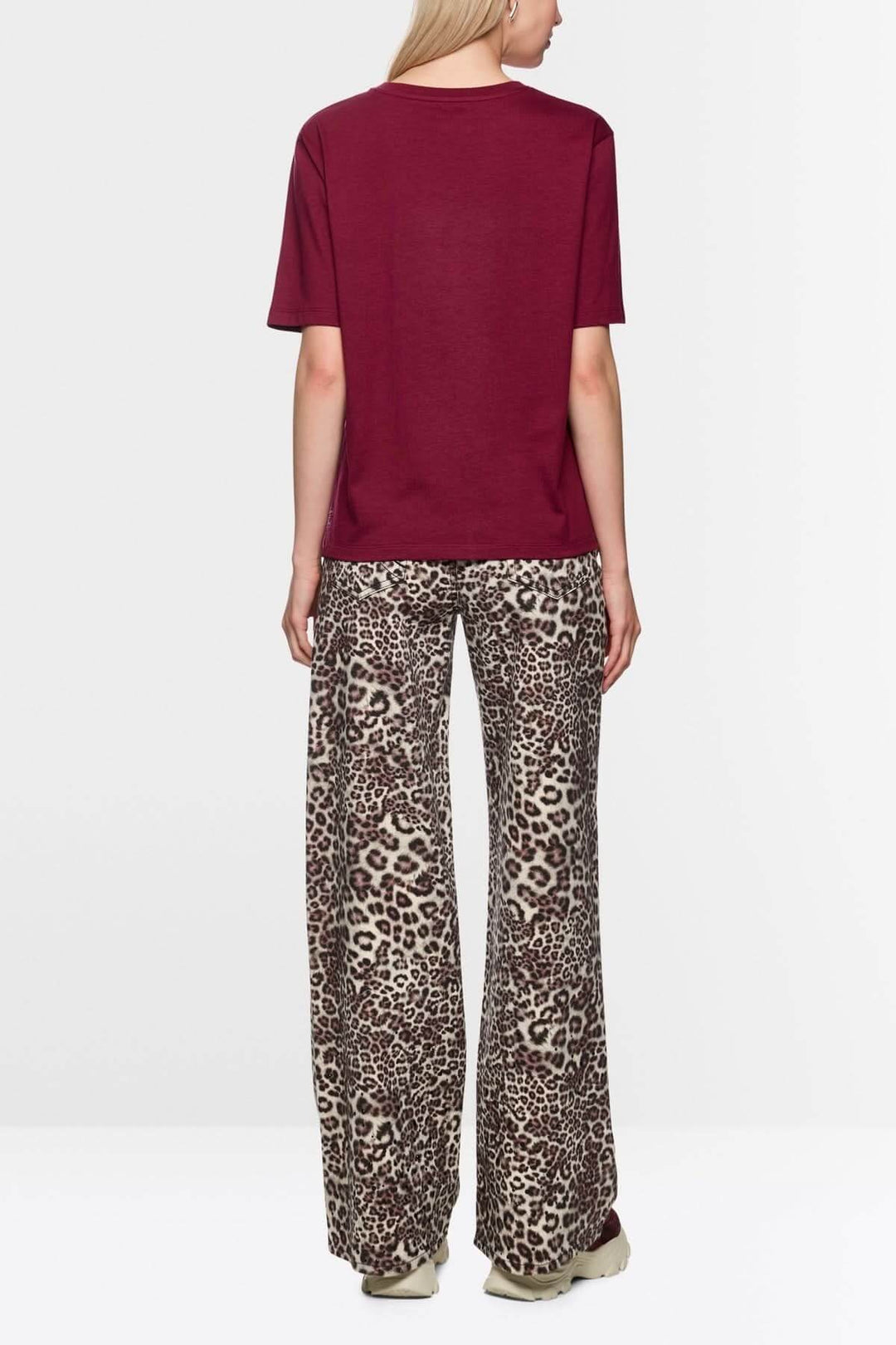 Person wearing T-shirt imprimé cerises léopard with burgundy top and leopard print pants, viewed from behind.