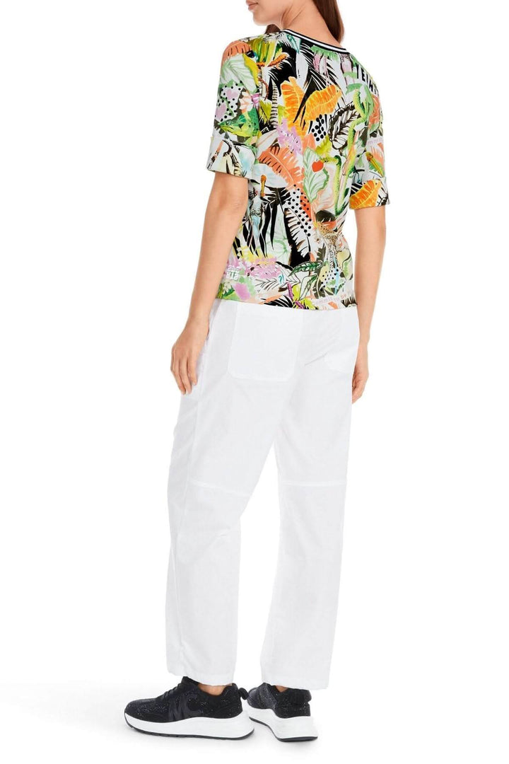 T-shirt imprimé jungle coupé slim, manches 3/4, motifs colorés, porté avec un pantalon blanc.