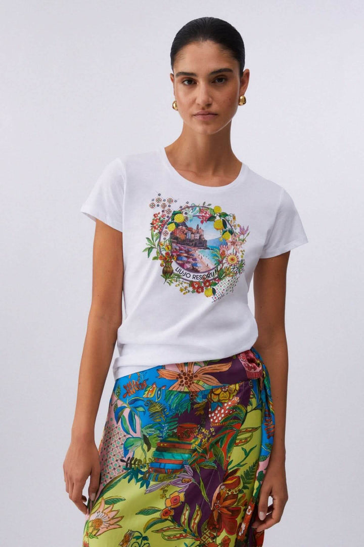 Femme portant un T-shirt à manches courtes avec imprimé graphique et jupe colorée, illustrant un style moderne et décontracté.
