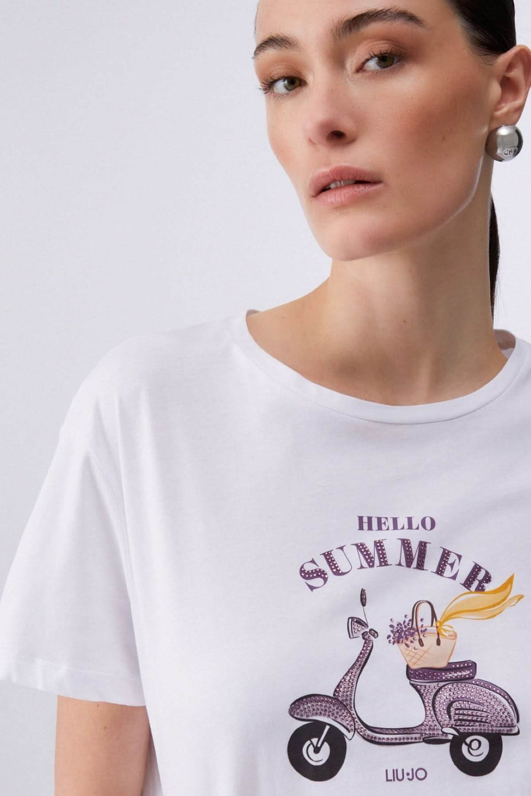 T-shirt à manches courtes avec imprimé graphique "Hello Summer" et dessin de scooter, porté par un modèle.