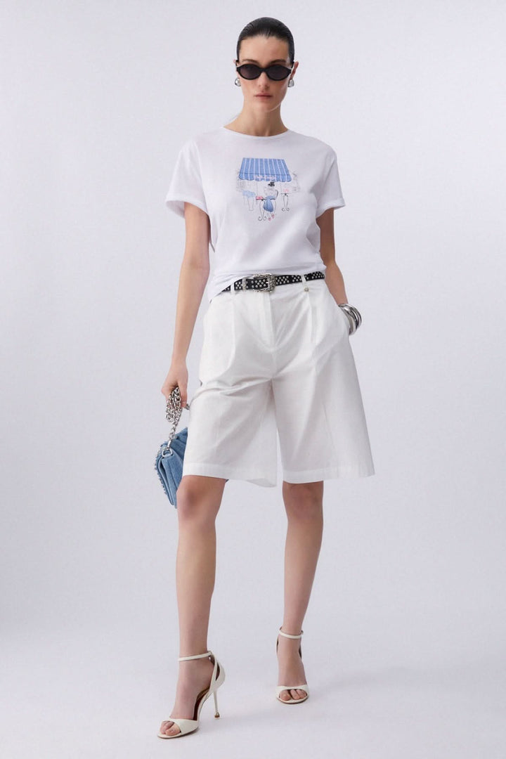 Femme portant un t-shirt à manches courtes avec imprimé graphique, style moderne et féminin, tenue décontractée et stylée.