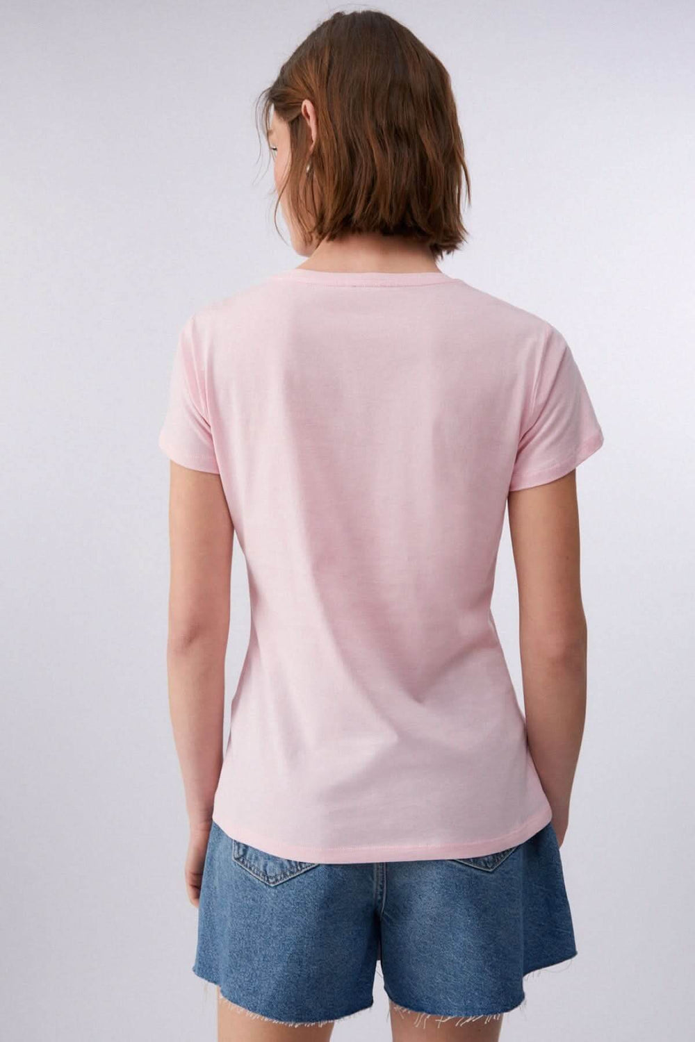 Vue arrière d'un t-shirt à manches courtes avec imprimé graphique, femme portant un short en jean, style décontracté moderne.