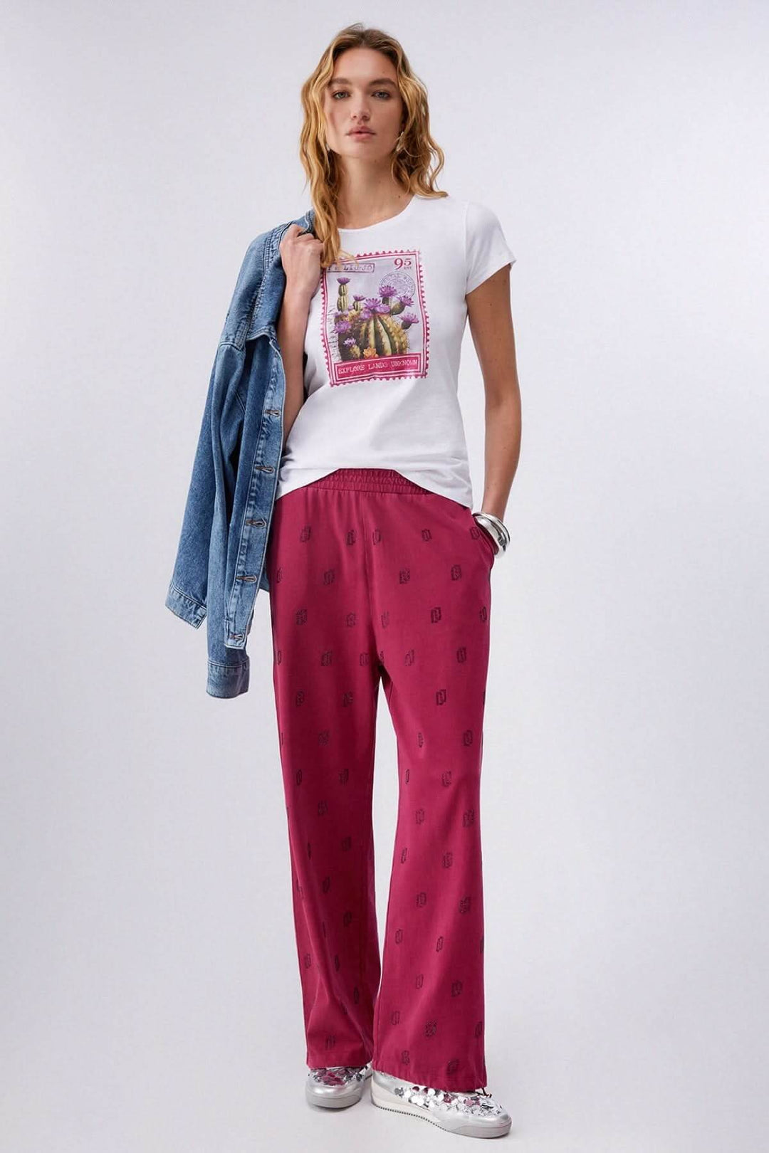 Femme portant un T-shirt à manches courtes avec imprimé graphique, style décontracté, veste en denim et pantalon rose.