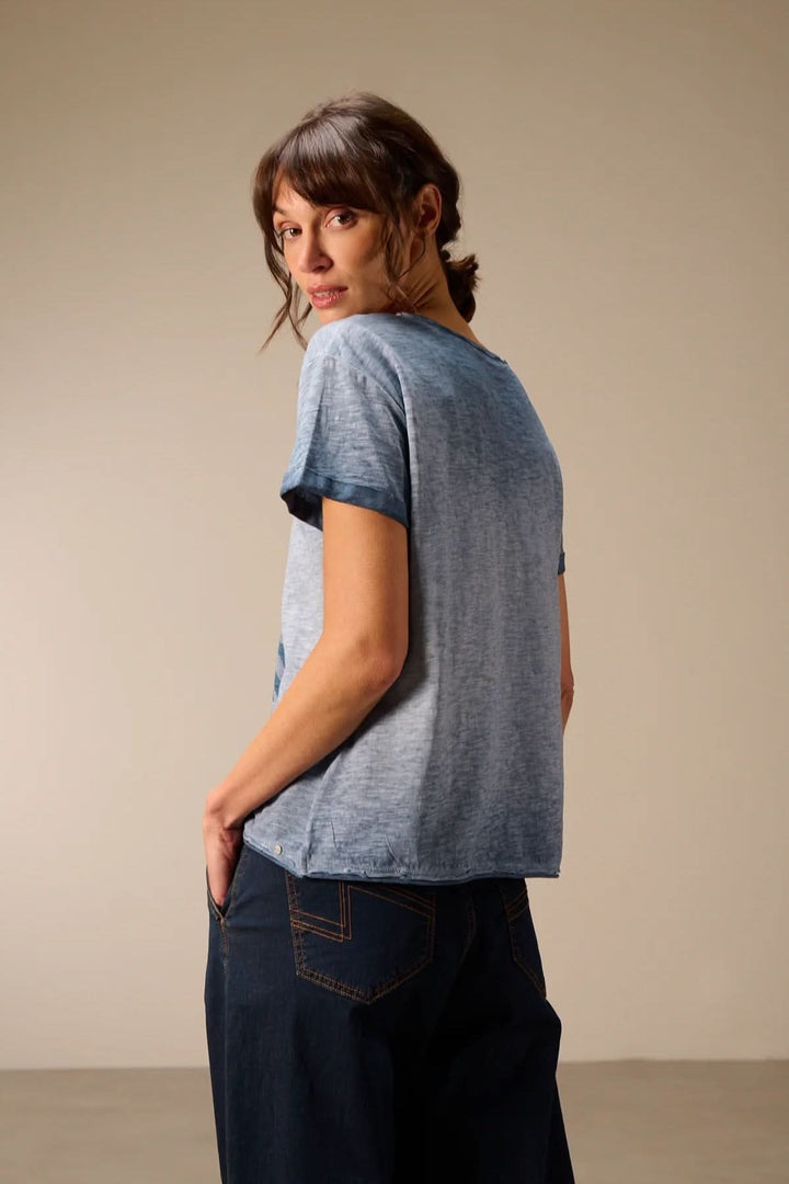 Femme portant un T-shirt à manches courtes coupe décontractée, silhouette fluide, manches courtes avec revers, tissu doux et respirant.