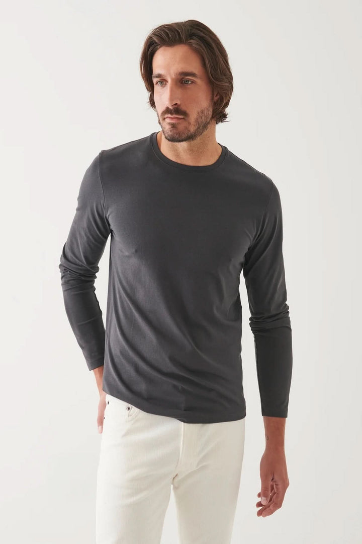 Homme portant un t-shirt à manches longues gris en tissu de coton Pima, look élégant avec un fond neutre.