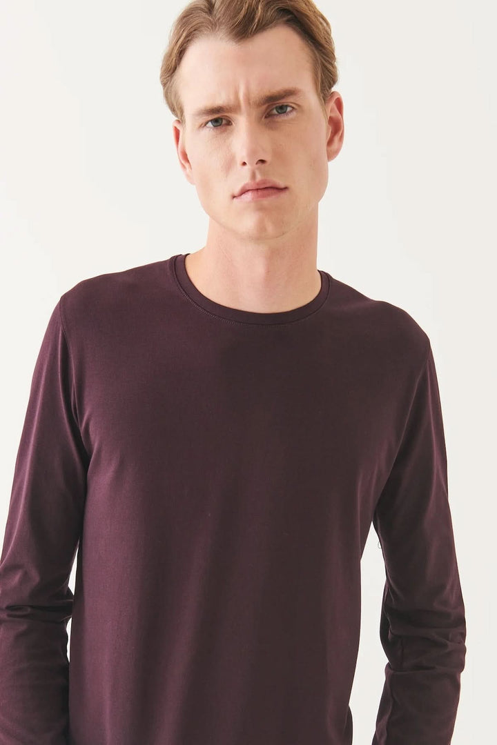Homme portant un t-shirt manches longues en coton Pima péruvien de couleur prune, col rond et coupe confortable.