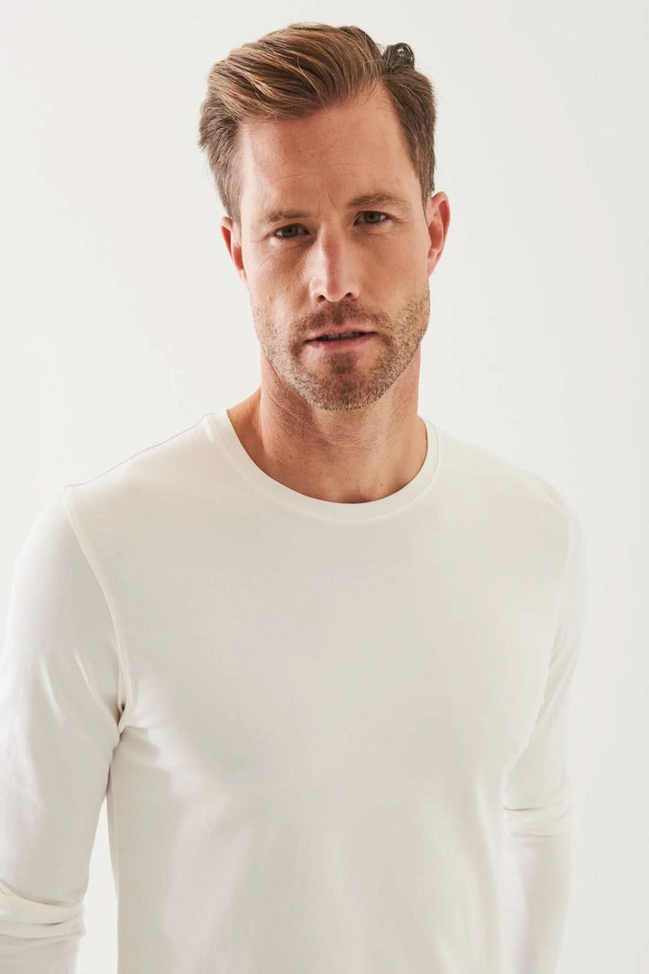 Homme portant un t-shirt blanc à manches longues, col rond en coton Pima péruvien, style décontracté.